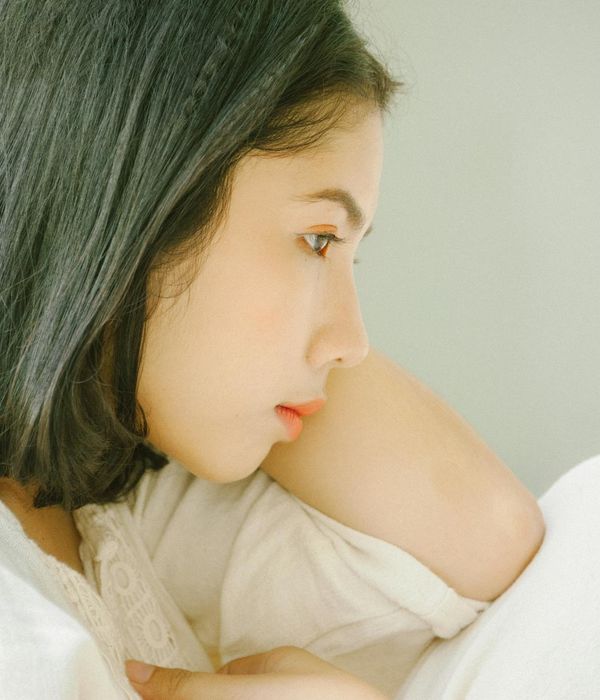 Serene woman in a thoughtful pose surrounded by soft light.